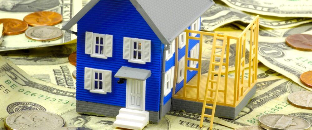 Miniature House sitting on Money depicting there is Equity in the house