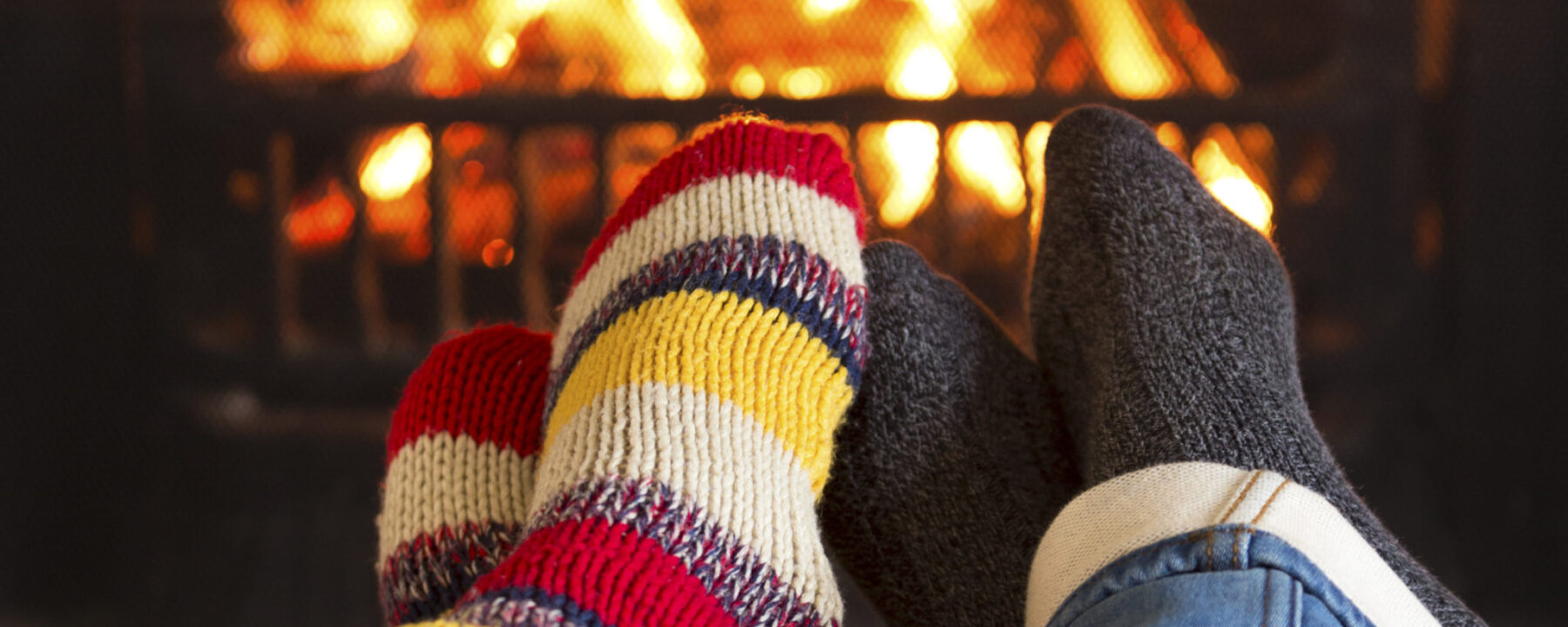 Couple's feet in woolen stocking in front of fire warming up